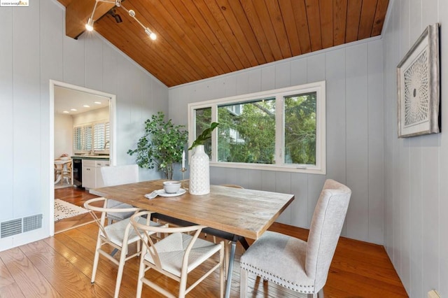 dining space featuring wooden walls, light hardwood / wood-style floors, lofted ceiling, and wood ceiling