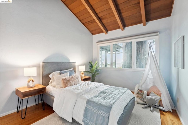 bedroom featuring vaulted ceiling with beams, light hardwood / wood-style flooring, and wooden ceiling