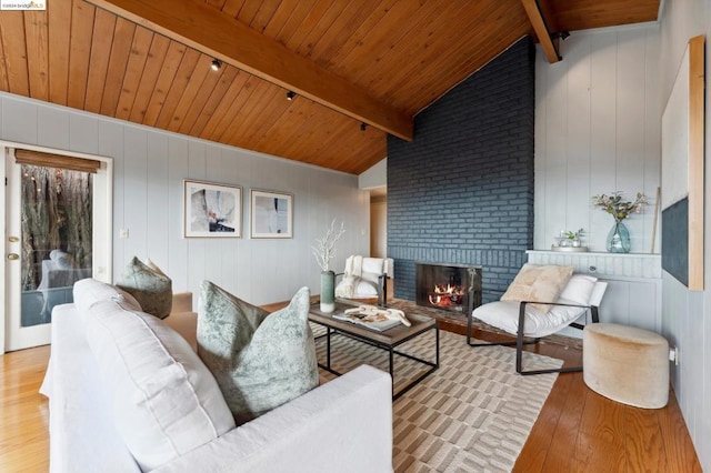 living room featuring light wood-type flooring, vaulted ceiling with beams, and wooden ceiling