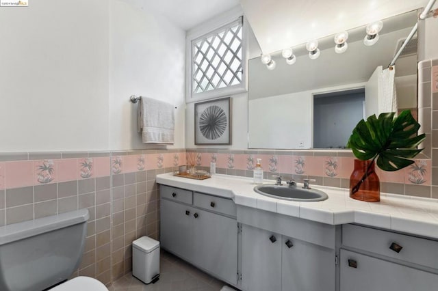 bathroom with tile patterned flooring, vanity, toilet, and tile walls