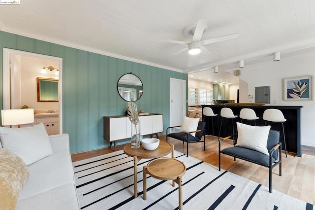 living room with ceiling fan, ornamental molding, and light wood-type flooring