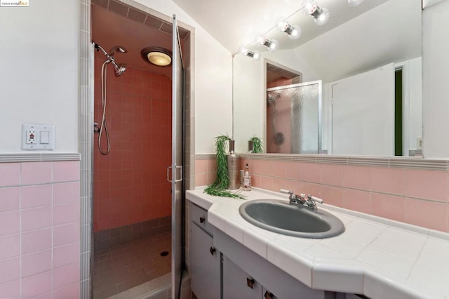 bathroom with walk in shower, vanity, and tile walls