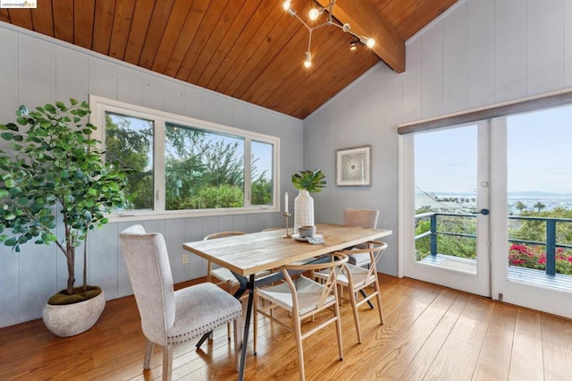 dining room featuring vaulted ceiling with beams, plenty of natural light, wooden ceiling, and light hardwood / wood-style flooring