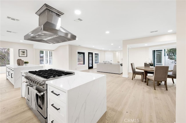 kitchen featuring white cabinets, a wealth of natural light, stainless steel range, and extractor fan