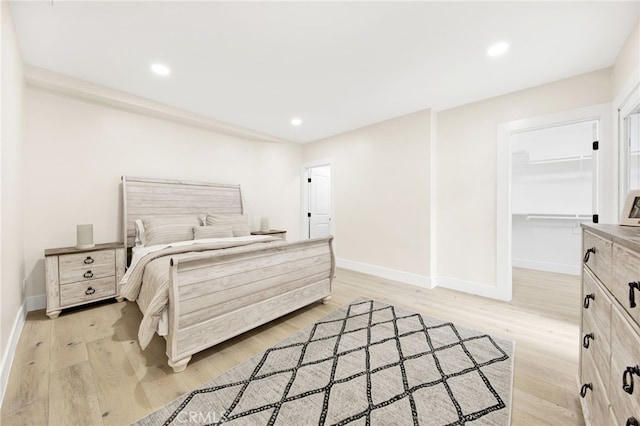 bedroom with light wood-type flooring, a walk in closet, and a closet