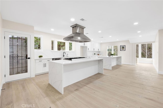 kitchen featuring a large island, light wood-type flooring, white cabinetry, and a wealth of natural light