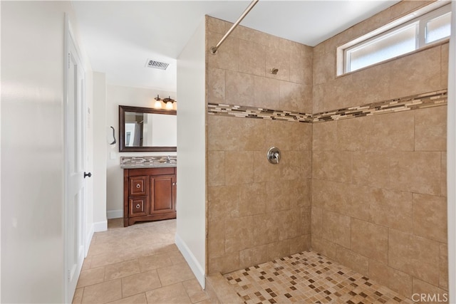 bathroom featuring vanity, a tile shower, and tile patterned floors