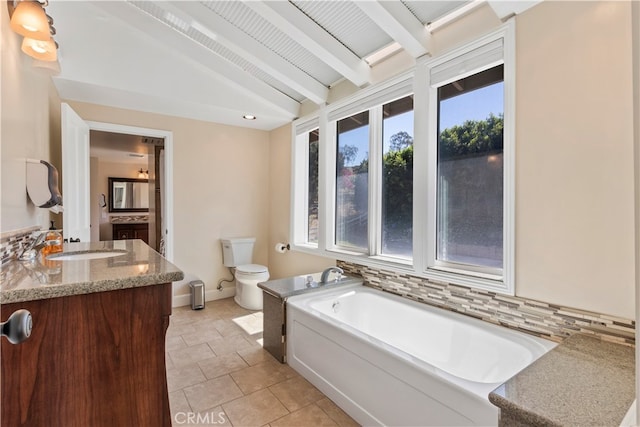 bathroom with vaulted ceiling with beams, vanity, a bathtub, tasteful backsplash, and toilet