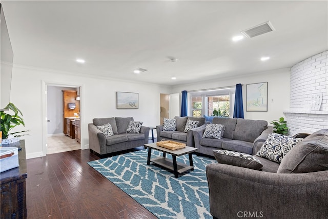 living room featuring a brick fireplace, ornamental molding, and dark hardwood / wood-style flooring