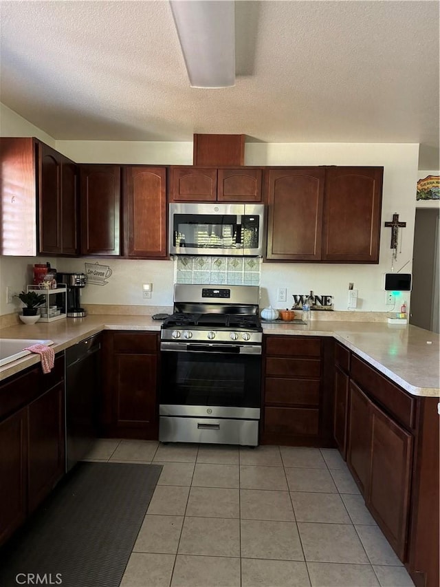 kitchen featuring kitchen peninsula, light tile patterned floors, stainless steel appliances, and a textured ceiling