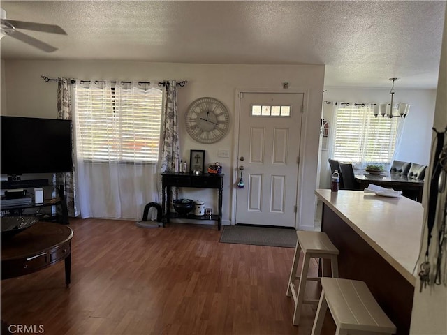 entrance foyer featuring ceiling fan with notable chandelier, wood-type flooring, and a textured ceiling