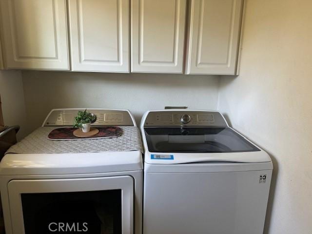 clothes washing area with cabinets and independent washer and dryer