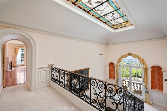 hall featuring light carpet, a skylight, and ornamental molding