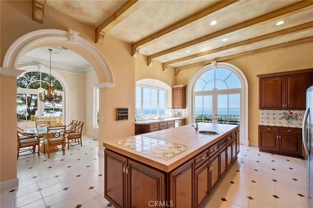 2736 Via Victoria, Palos Verdes Estates, CA 90274 - kitchen featuring light countertops, a sink, a center island with sink, beamed ceiling, and an inviting chandelier