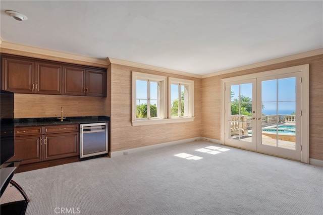 kitchen featuring ornamental molding, sink, french doors, beverage cooler, and light carpet