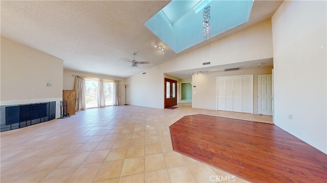 unfurnished living room featuring ceiling fan, light tile patterned flooring, a textured ceiling, and high vaulted ceiling