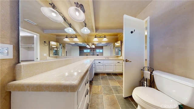 bathroom with vanity, beam ceiling, and toilet