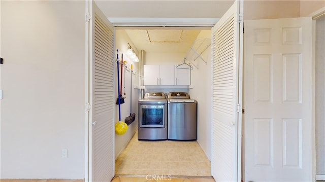 clothes washing area featuring washing machine and dryer and cabinets