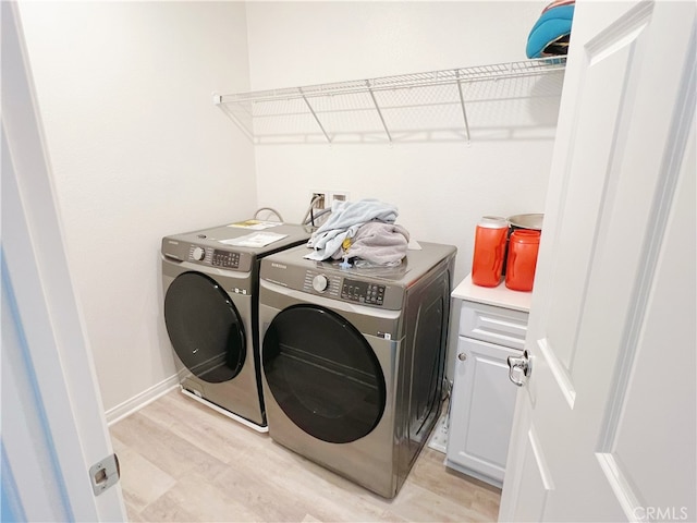 washroom featuring cabinets, light wood-type flooring, and washer and clothes dryer