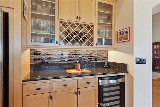 bar with dark stone counters, wine cooler, decorative backsplash, hardwood / wood-style floors, and light brown cabinetry