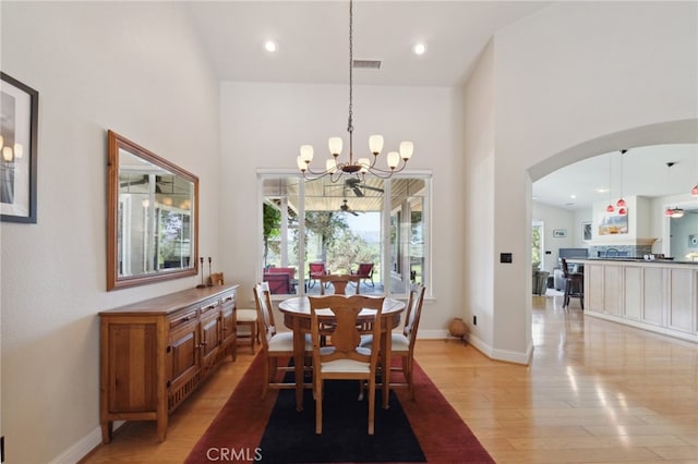 dining room featuring light wood-type flooring, a chandelier, and a high ceiling