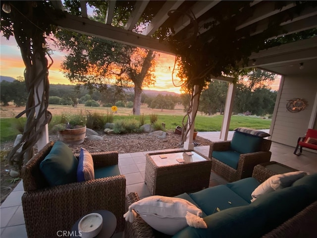 patio terrace at dusk featuring an outdoor hangout area and a lawn