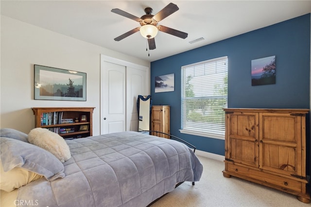 bedroom with ceiling fan, light colored carpet, and a closet