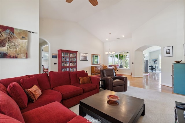 living room with ceiling fan with notable chandelier, light wood-type flooring, and high vaulted ceiling