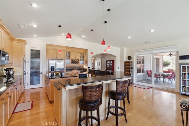 kitchen featuring a large island, lofted ceiling, light hardwood / wood-style flooring, stainless steel appliances, and decorative light fixtures