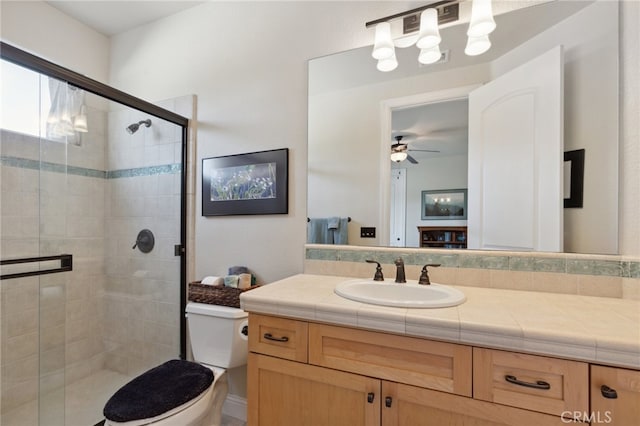 bathroom featuring vanity, toilet, ceiling fan, and a shower with shower door