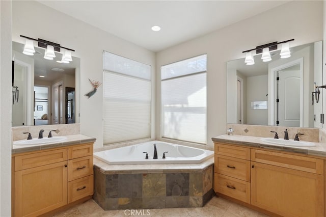 bathroom with tile patterned floors, tiled bath, and vanity