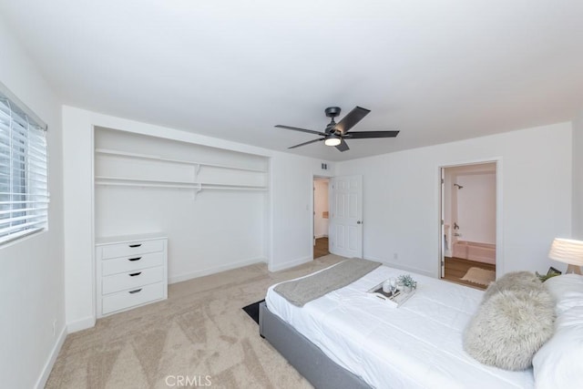 bedroom featuring connected bathroom, ceiling fan, a closet, and light carpet