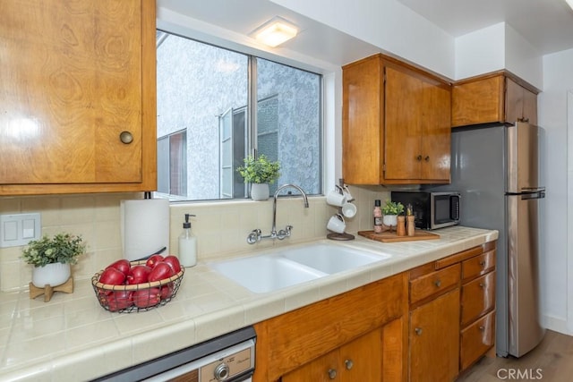 kitchen with backsplash, tile countertops, sink, and stainless steel appliances