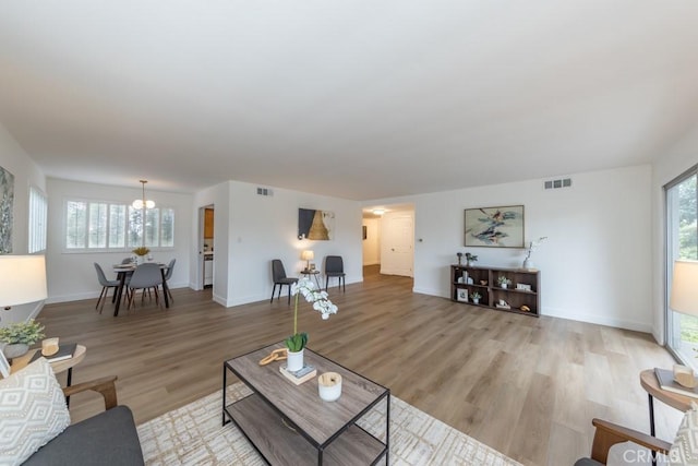 living room featuring light wood-type flooring, a wealth of natural light, and a notable chandelier