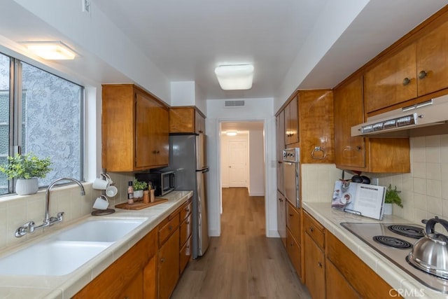 kitchen featuring decorative backsplash, light wood-type flooring, sink, and stainless steel appliances