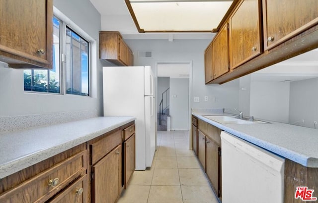 kitchen with light tile patterned floors, white appliances, and sink