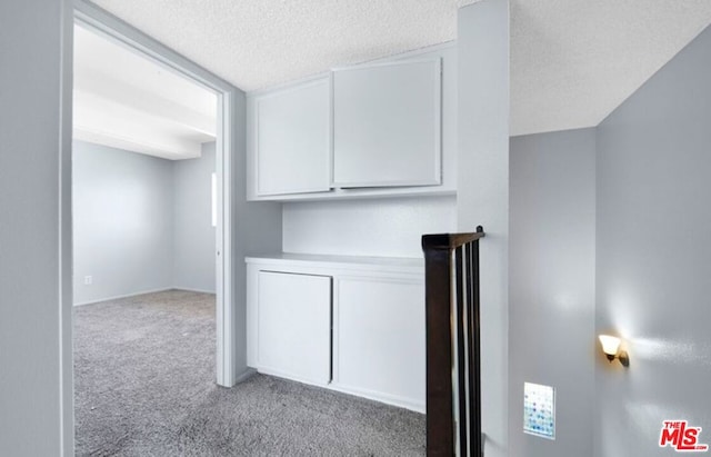 interior space with a textured ceiling and light carpet