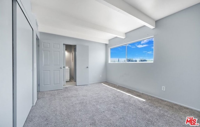 unfurnished bedroom featuring light carpet and beamed ceiling