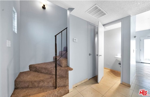 stairway with tile patterned flooring and a textured ceiling