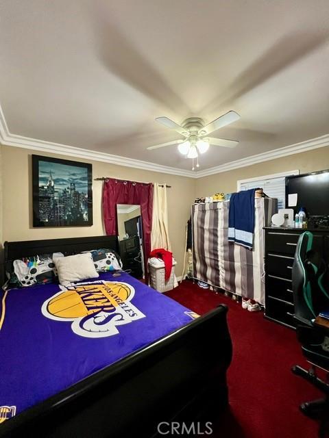 carpeted bedroom featuring ceiling fan and ornamental molding
