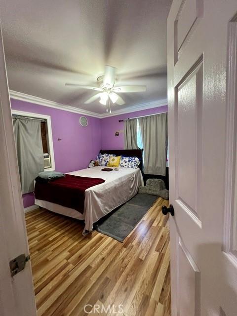 bedroom featuring crown molding, light wood-type flooring, and ceiling fan