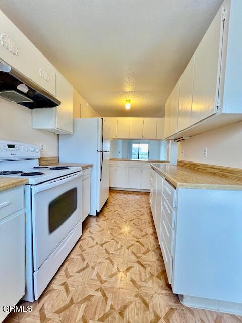 kitchen with white cabinets, white appliances, and light parquet floors