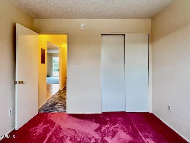 unfurnished bedroom with a closet, carpet, and a textured ceiling