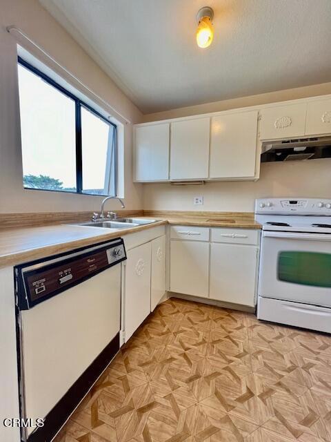 kitchen featuring white cabinets, white appliances, light parquet floors, and sink