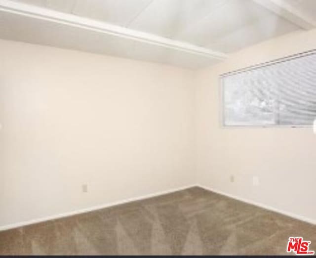 empty room featuring dark colored carpet and beam ceiling