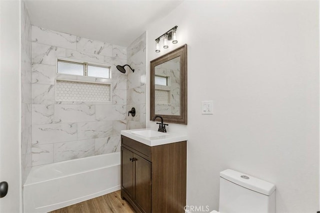 full bathroom with hardwood / wood-style flooring, vanity, toilet, and tiled shower / bath