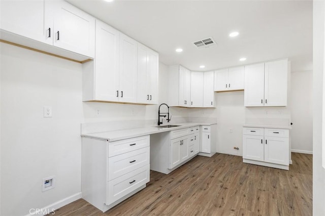 kitchen with hardwood / wood-style flooring, white cabinets, and sink