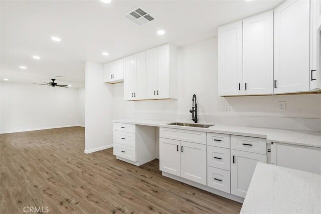 kitchen with white cabinets, ceiling fan, sink, and hardwood / wood-style floors