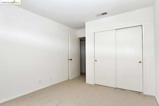 unfurnished bedroom with a closet and light colored carpet