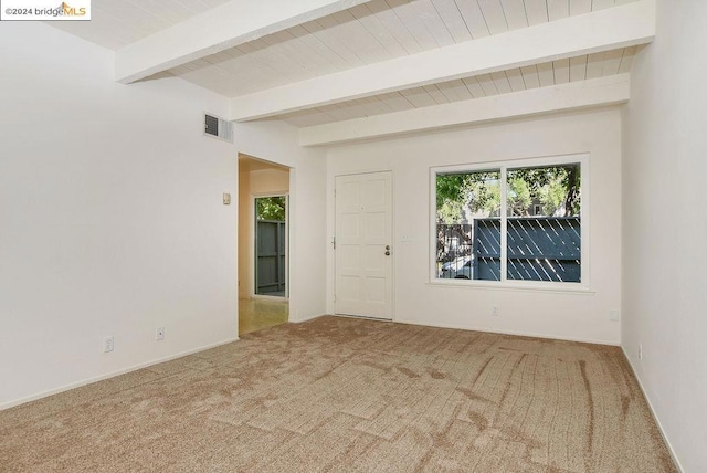 spare room featuring carpet and beamed ceiling